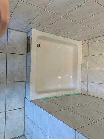 Duschwanne in gefliestem Badezimmer mit sichtbarer Silikonfuge und Wandfliesen.