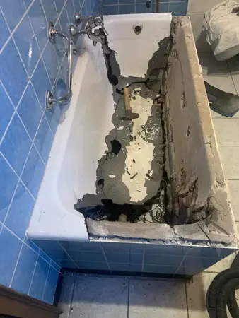 Beschädigte Badewanne während einer Badsanierung mit sichtbaren Fliesen und Werkzeugen.