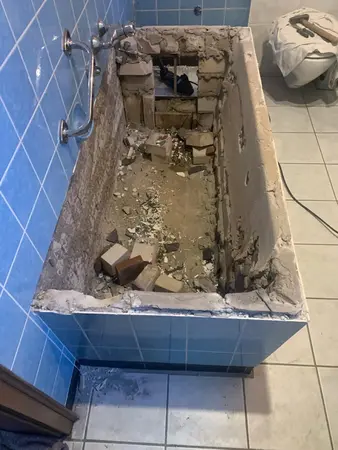 Alte Badewanne im Badezimmer wird abgerissen, Bauschutt und Fliesen liegen im Inneren.
